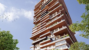 Foto zeigt einen Wohnbauturm mit Bäumen links und rechts