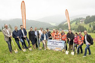 Foto von mehreren Personen beim Spatenstich des PV-Parks Ratten, diese stehen auf einer grünen Wiese