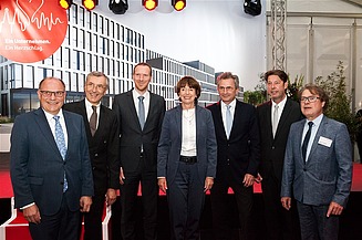 Foto von sieben Personen, die vor einem Plakat stehen