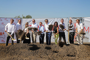 Foto von mehreren Personen mit Schaufeln in der Hand bei einem symbolischen Spatenstich