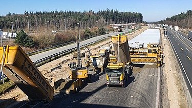 Foto von mehreren Straßenbaumaschinen beim Einbau einer Betondecke