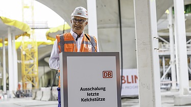 Foto von einer Person in Schutzausrüstung die eine Rede hält.    