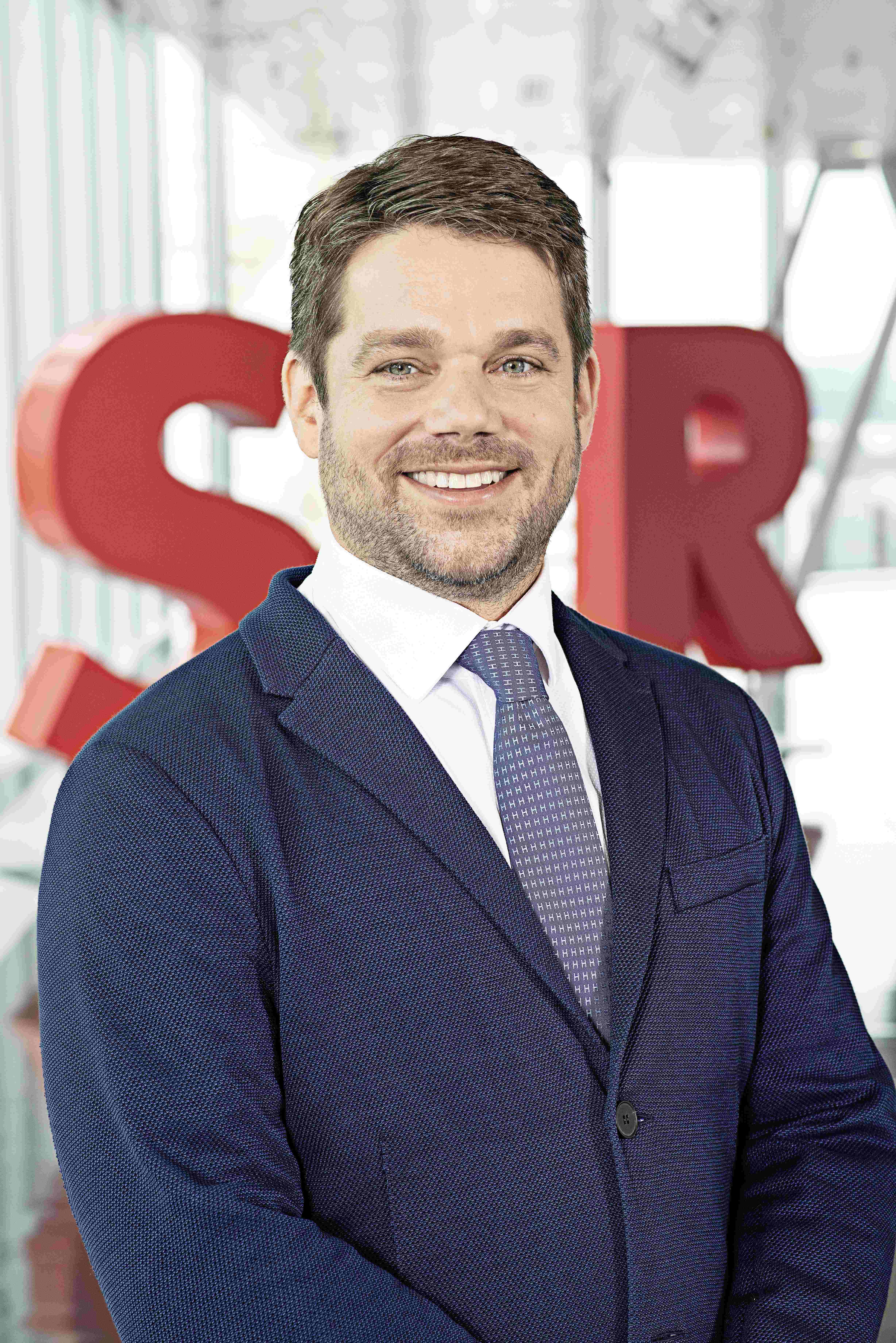 Photo of Klemens Haselsteiner standing in front of the red letters STRABAG