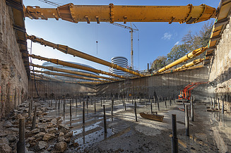 Foto von einem Loch auf einer Baustelle. Am Boden des Lochs sind Metallstäbe. 