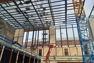 Foto von einer Baustelle von innen. Es ist ein Kran und Hebebühnen zusehen. 