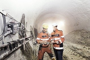 Foto von zwei Tunnelbauarbeitern bei einer Maschine