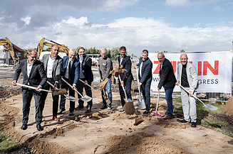 Das Bild zeigt Personen beim Spatenstich mit Schaufeln.