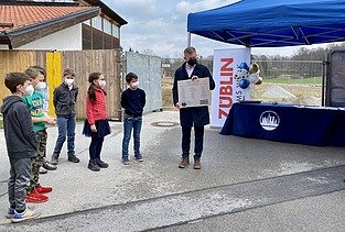 Foto von Kindern und einem Mann, die an einer Zeitkapsel-Zeremonie teilnehmen. 