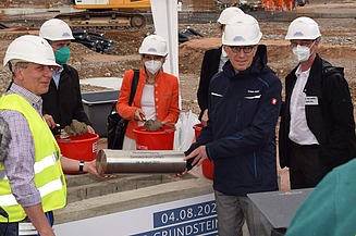 Foto von der Grundsteinlegung im Klinikum, mehrere Personen halten eine Zeitkapsel. 