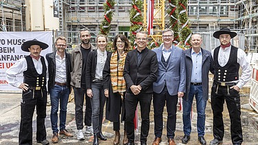 Foto von mehreren schick gekleideten Personen auf einer Baustelle.  