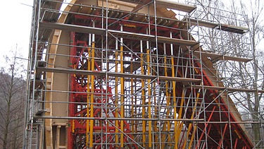  Foto von einem Bogen um den ein Gerüst gebaut ist.