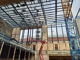 Foto von einer Baustelle von innen. Es ist ein Kran und Hebebühnen zusehen. 