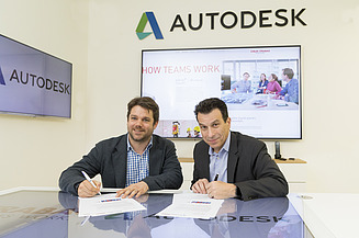 Foto von zwei Personen bei einer Vertragsunterzeichung, dahinter ein Bildschirm, darüber die Aufschrift Autodesk