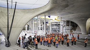 Foto von mehreren Personen in Schutzausrüstung auf einer Baustelle.   
