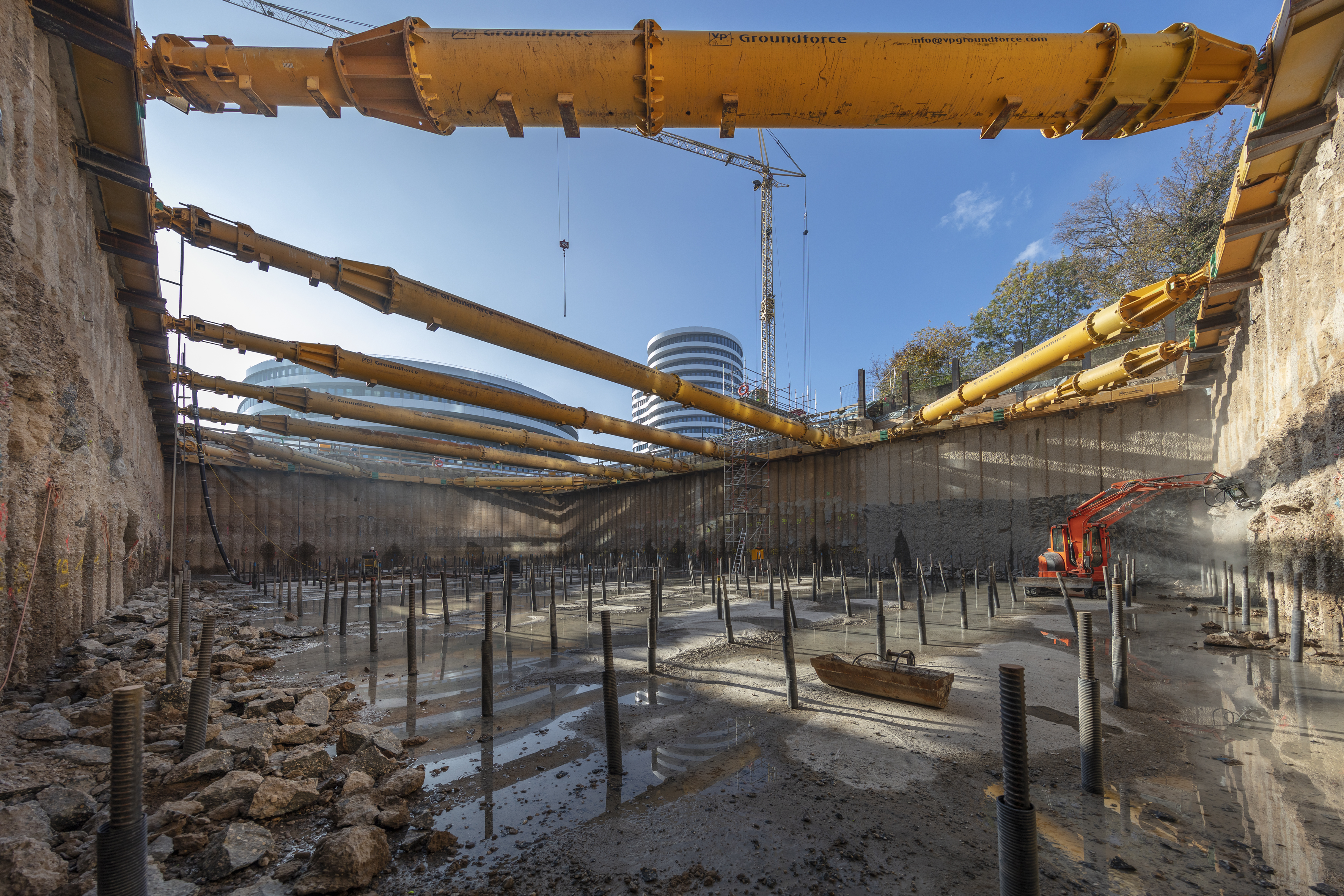 Foto von einem Loch auf einer Baustelle. Am Boden des Lochs sind Metallstäbe. 