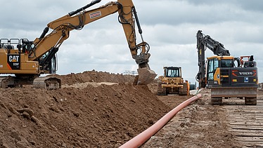 Photo of three working machines on a construction site.   