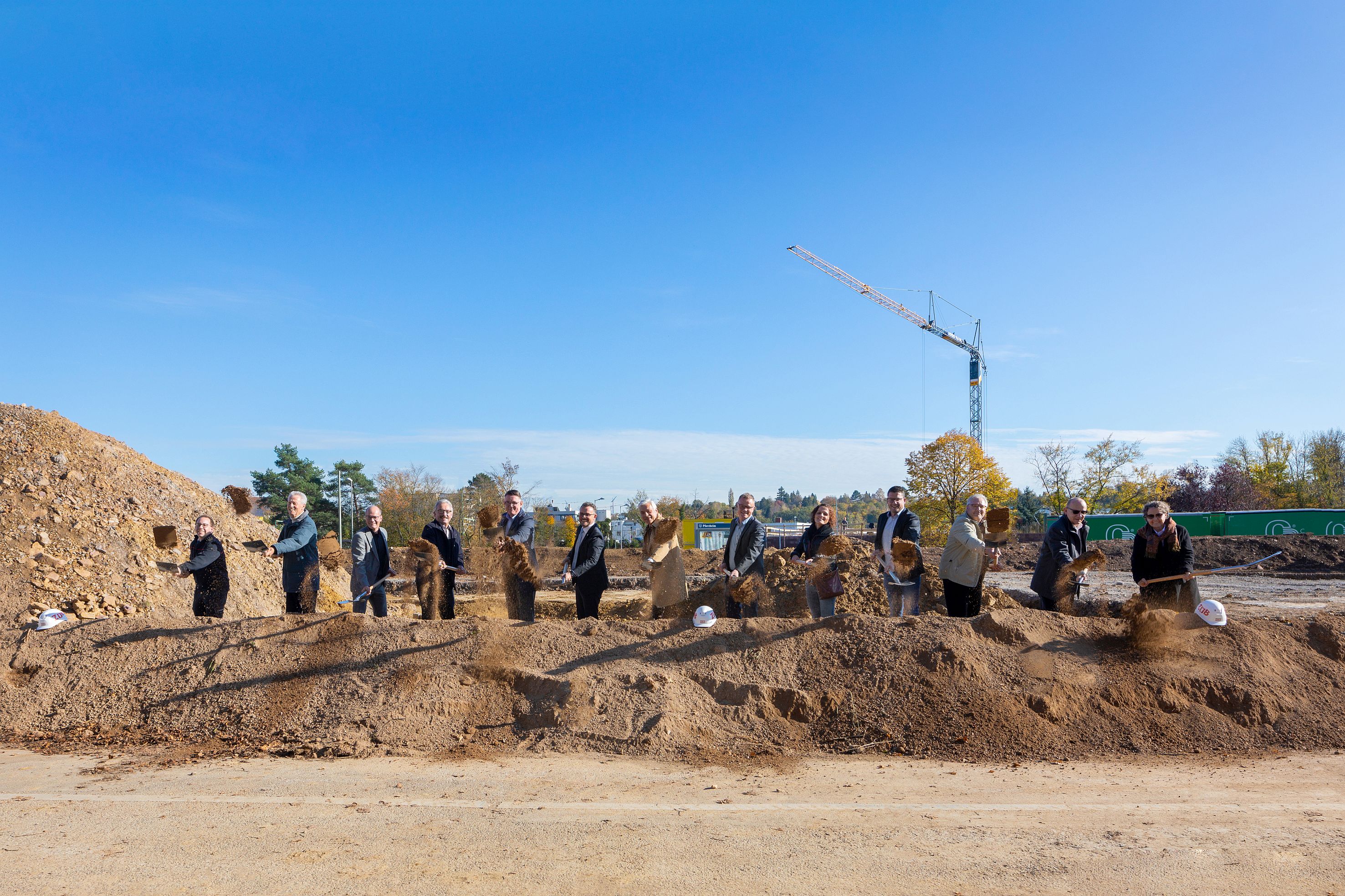 Foto von mehreren Männern auf einer Baustelle die mit einen Sparten Erde in die Luft werfen. 
