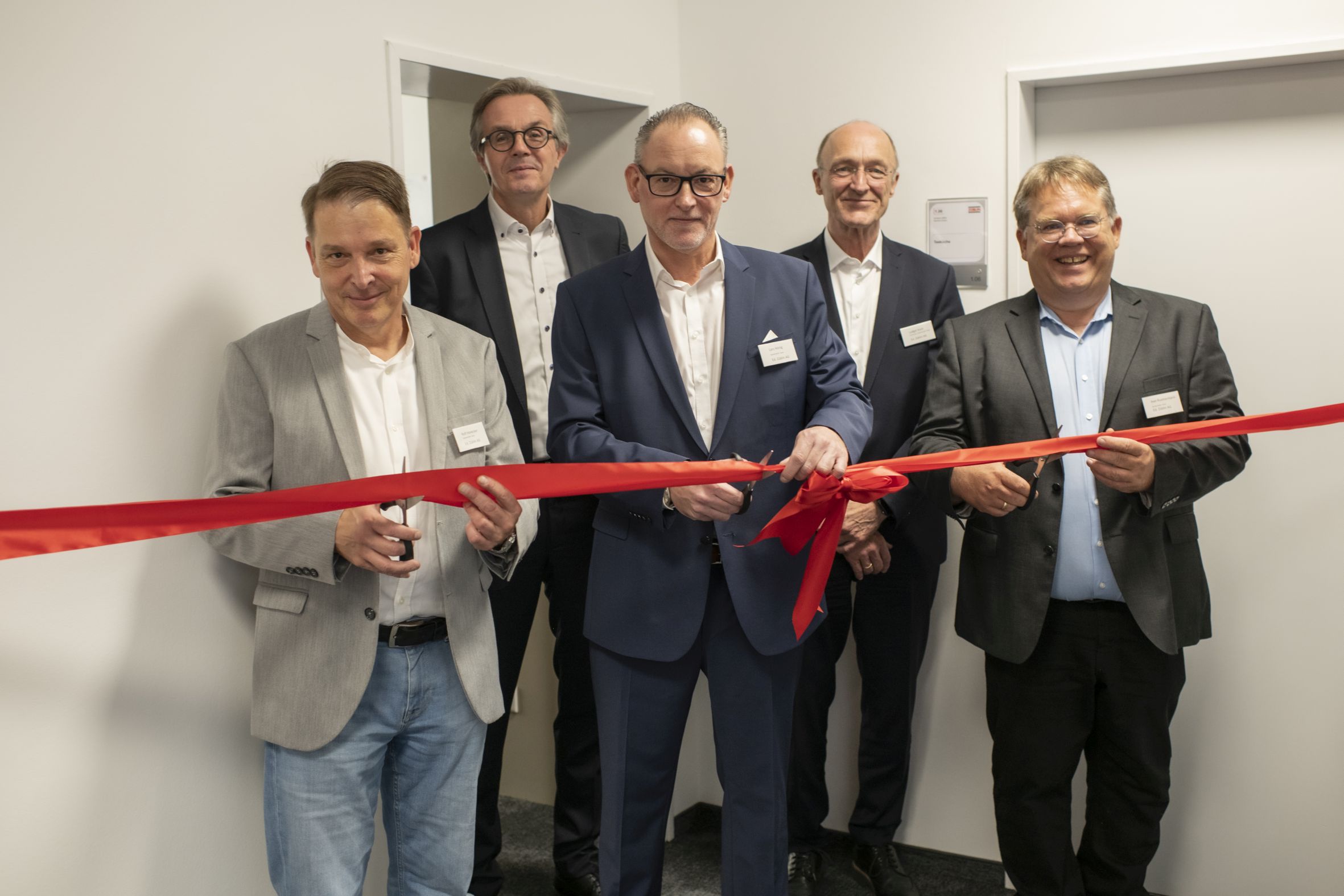Foto von mehreren Personen die ein Einweihungsband durchschneiden.  