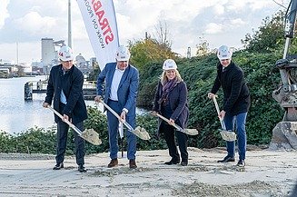 Foto von vier Personen mit Schaufeln, die einen Spatenstich durchführen, dahinter ein STRABAG Segelbanner