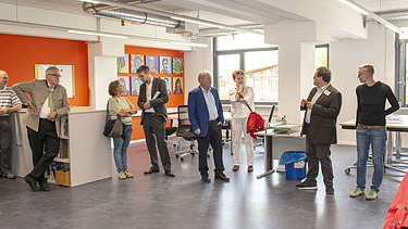 Foto von sich unterhaltenden Personen in einem Semianraum. 