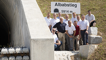 Foto von freundlich schauenden Männern, die neben einem Tunell stehen. 