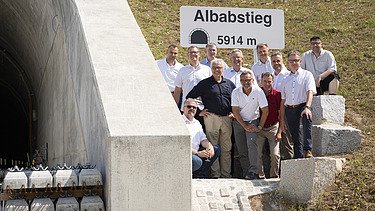 Foto von freundlich schauenden Männern, die neben einem Tunell stehen. 