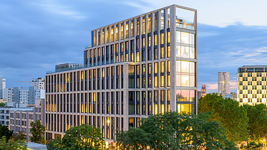 Wide skyscraper behind green trees