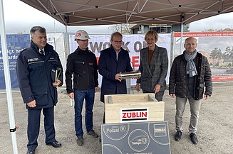 Foto mehreren Personen die eine Röhre in eine Holztruhe legen.   