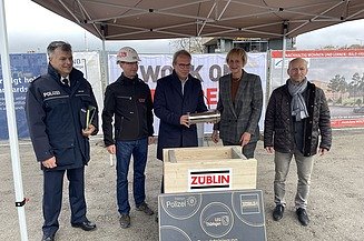Foto mehreren Personen die eine Röhre in eine Holztruhe legen.   