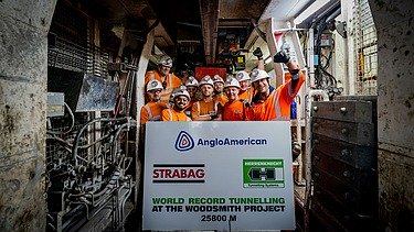 Foto von mehreren Personen, die einen Tunneldurchstich feiern und eine große Tafel in der Hand halten