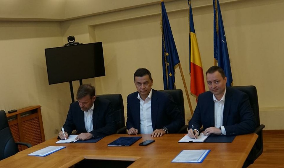 Photo of a contract signing with three people sitting at a table