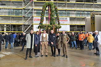 Foto von mehreren Personen vor dem Richtkranz von der Baustelle des Gymnasiums in Köln Deutz. 