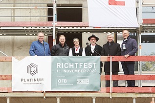 Foto von mehreren Personen auf einem Gerüst, beim Richtspruch. 