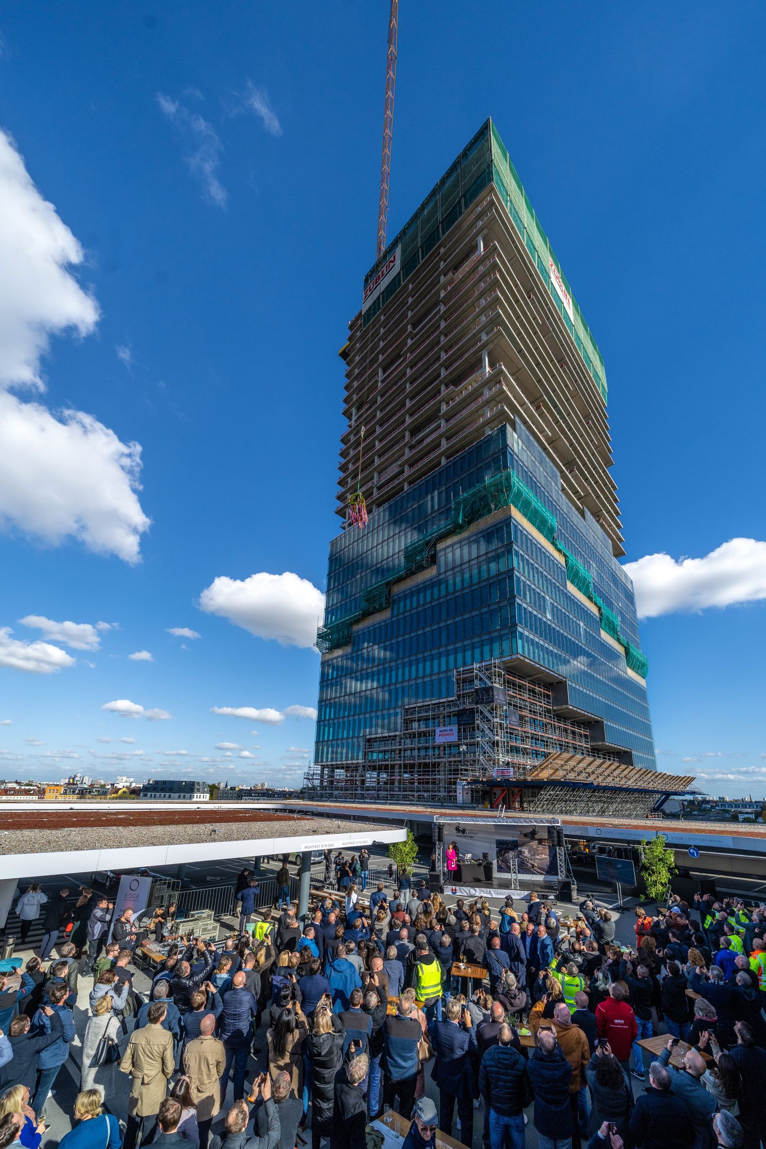 Luftaufnahme vom Richtfest mehrere Personen sind vor dem EDGE East Side versammelt.  