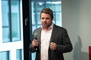 Foto von Klemens Haselsteiner im Anzug mit Microphon in der Hand. 