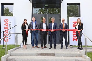 Foto von mehreren Personen bei der Einweihung des neuen Erweiterungsbaus der ZÜBLIN-Direktion in Karlsruhe, die ein rotes Band durchschneiden. 