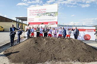 Das Bild zeigt mehrere Personen hinter einem Erdhaufen beim symbolischen Spatenstich