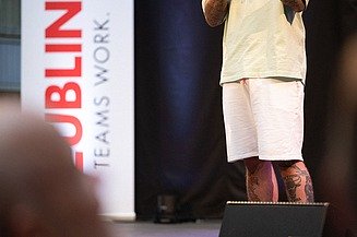 Foto von zwei Personen auf der Bühne. Sie spricht in ein Mikrophon.  