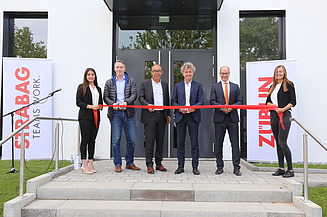Foto von mehreren Personen bei der Einweihung des neuen Erweiterungsbaus der ZÜBLIN-Direktion in Karlsruhe, die ein rotes Band durchschneiden. 