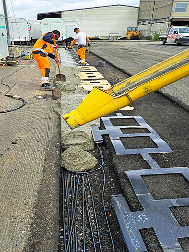 Foto von zwei Straßenbauarbeitern mit einer gelben Maschine