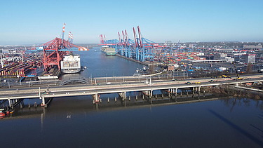 Foto eines Industriehafens davor führt eine Brücke über das Wasser