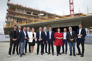 Foto von einer Gleichenfeier, mehrere Personen stehen vor einem Rohbau