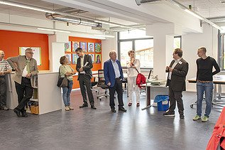 Foto von sich unterhaltenden Personen in einem Semianraum. 
