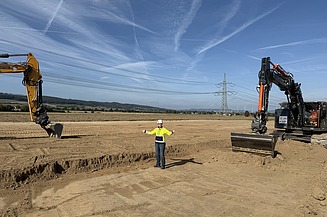 Photo of two construction workers with a machine doing civil engineering work in a trench
