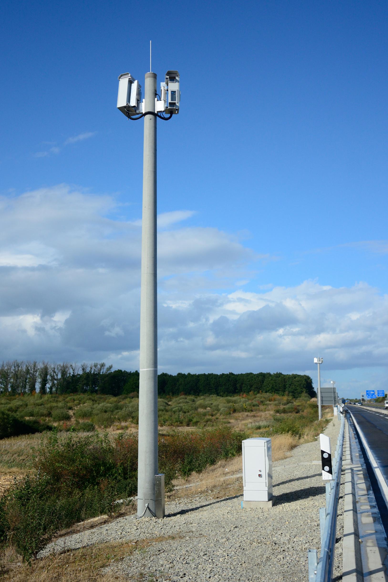 Foto eines Mastes mit einem technischen Gerät auf der Spitze, bei blauem Himmel