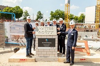 Foto von mehreren Personen, die freundlich schauen bei der Grundsteinlegung. 