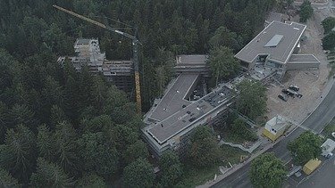 Foto in der Vogelperspektive von einem Wald in dem sich eine Baustelle befindet. 