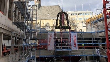 Richtfestkranz wird auf der Baustelle Antoniter Quartier in Köln gehisst. 