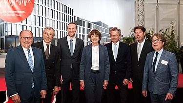 Foto von sieben Personen, die vor einem Plakat stehen
