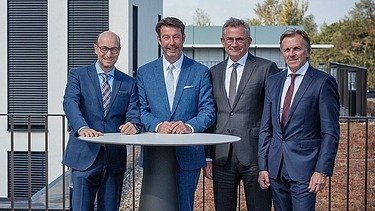 Foto von vier Personen, die an einem Stehtisch stehen